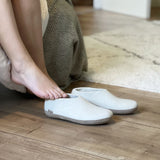 Person wearing white slippers on a wooden floor