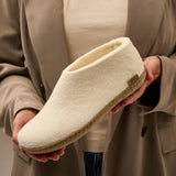 Person holding a white slipper with a neutral background