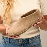 Person holding a sand slipper against a neutral background