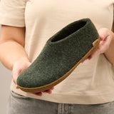 Person holding a forest green slipper with a honey rubber sole