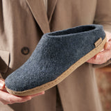 Denim slipper held by a person wearing a beige coat