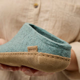 Close-up of a north sea slipper with a leather sole held by a person wearing a beige shirt.