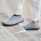 Gray slippers with rubber soles worn by a person on a stone surface