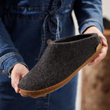 Person holding a dark gray slipper with a rubber sole