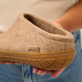 Sand slipper held by a person wearing blue jeans