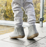 Child outside wearing grey wool boots with a beige leather sole.