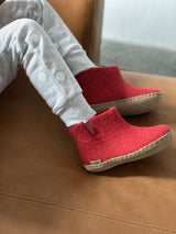 Child wearing little red wool boots with a beige leather sole.