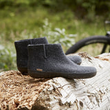 Pair of gray ankle boots on a log with a blurred natural background