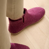 Cranberry slippers worn indoors on a wooden floor