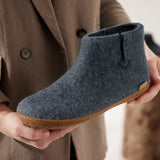 Person holding a blue felt shoe with a honey rubber sole