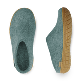 Pair of teal slippers with natural rubber soles on a white background
