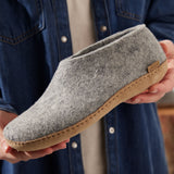 Person holding a gray slipper with a brown sole