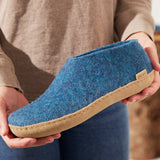 Blue slipper with brown sole held by a person wearing a beige sweater.
