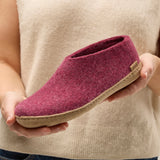 Person holding a cranberry felted shoe with a beige sole