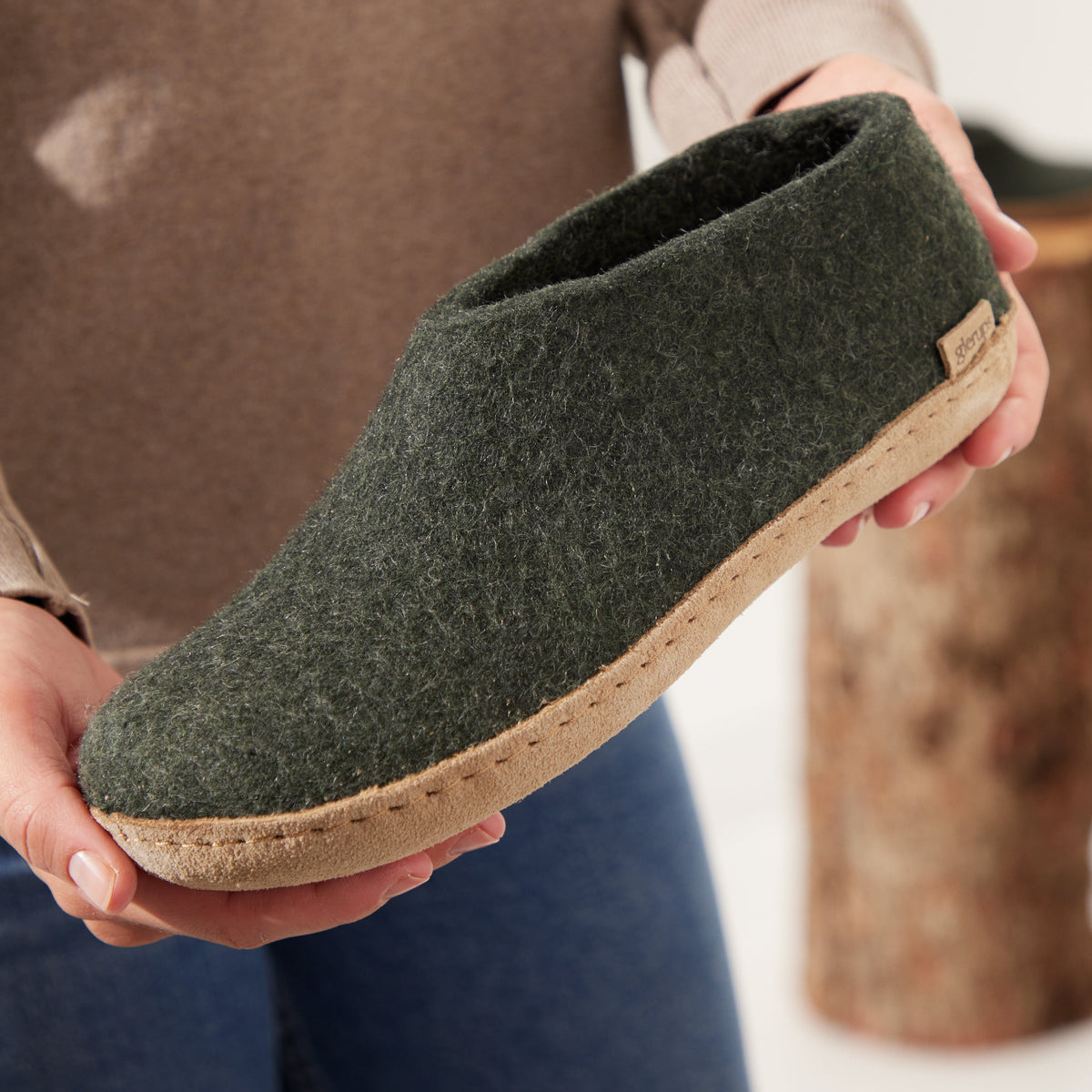 Person holding a green slipper with a cork sole