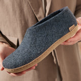Blue slipper held by a person wearing a beige coat