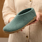 Person holding a North Sea felt slipper with a brown sole against a beige background