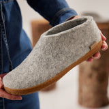 Gray slipper with honey rubber sole held by a person wearing blue jeans.