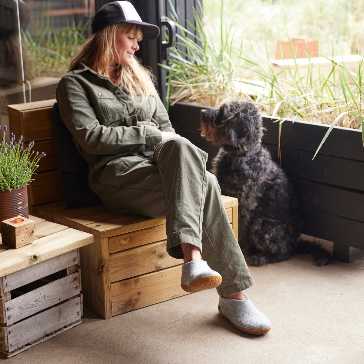 Woman sitting on a wooden bench with a dog in a garden setting