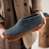 Person holding a blue slipper with a honey rubber sole