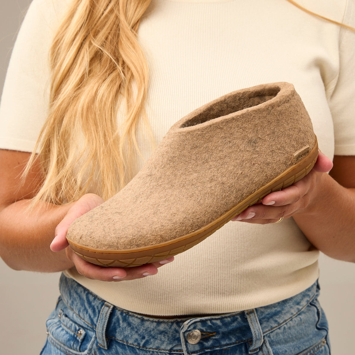 Person holding a sand slipper with a neutral background