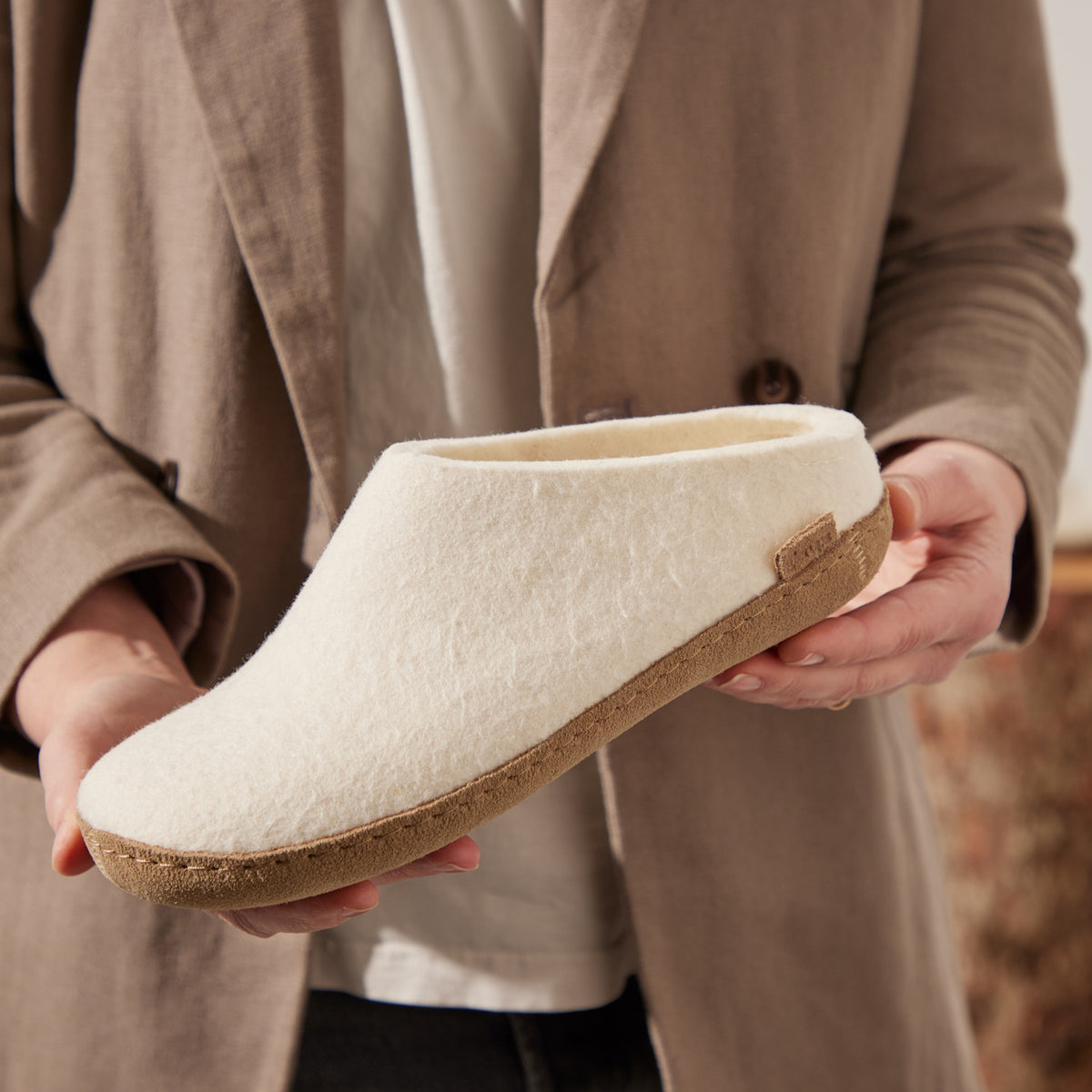 Person holding a white slipper with leather sole