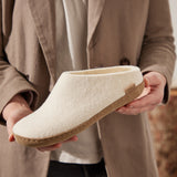 Person holding a white slipper with leather sole