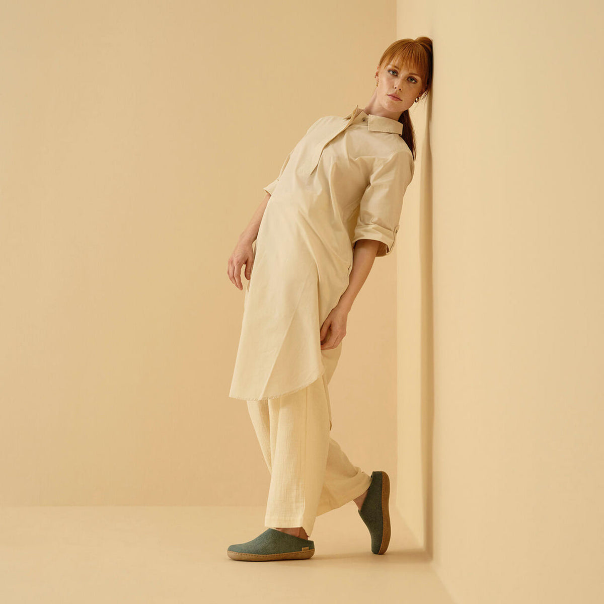 Woman wearing north sea slippers against a beige wall