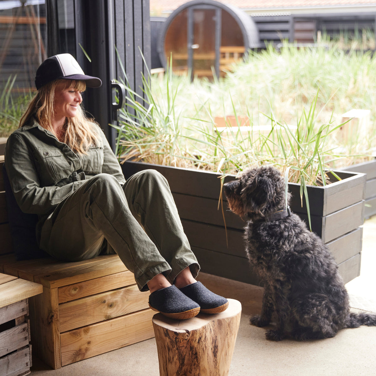 Woman sitting on a wooden bench with a dog in an outdoor setting
