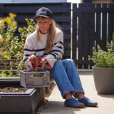Woman sitting outdoors with gardening tools and plants
