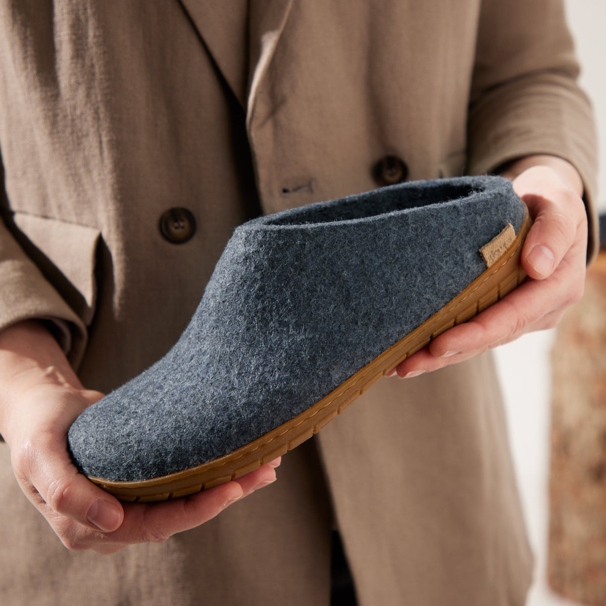 Person holding a denim slipper with a brown sole