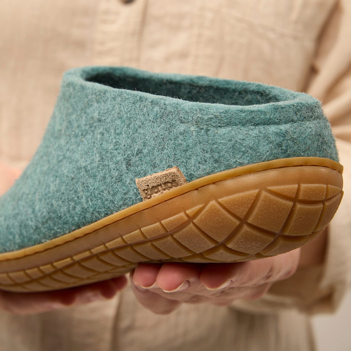 North sea slipper with rubber sole held by a person wearing a beige sweater.