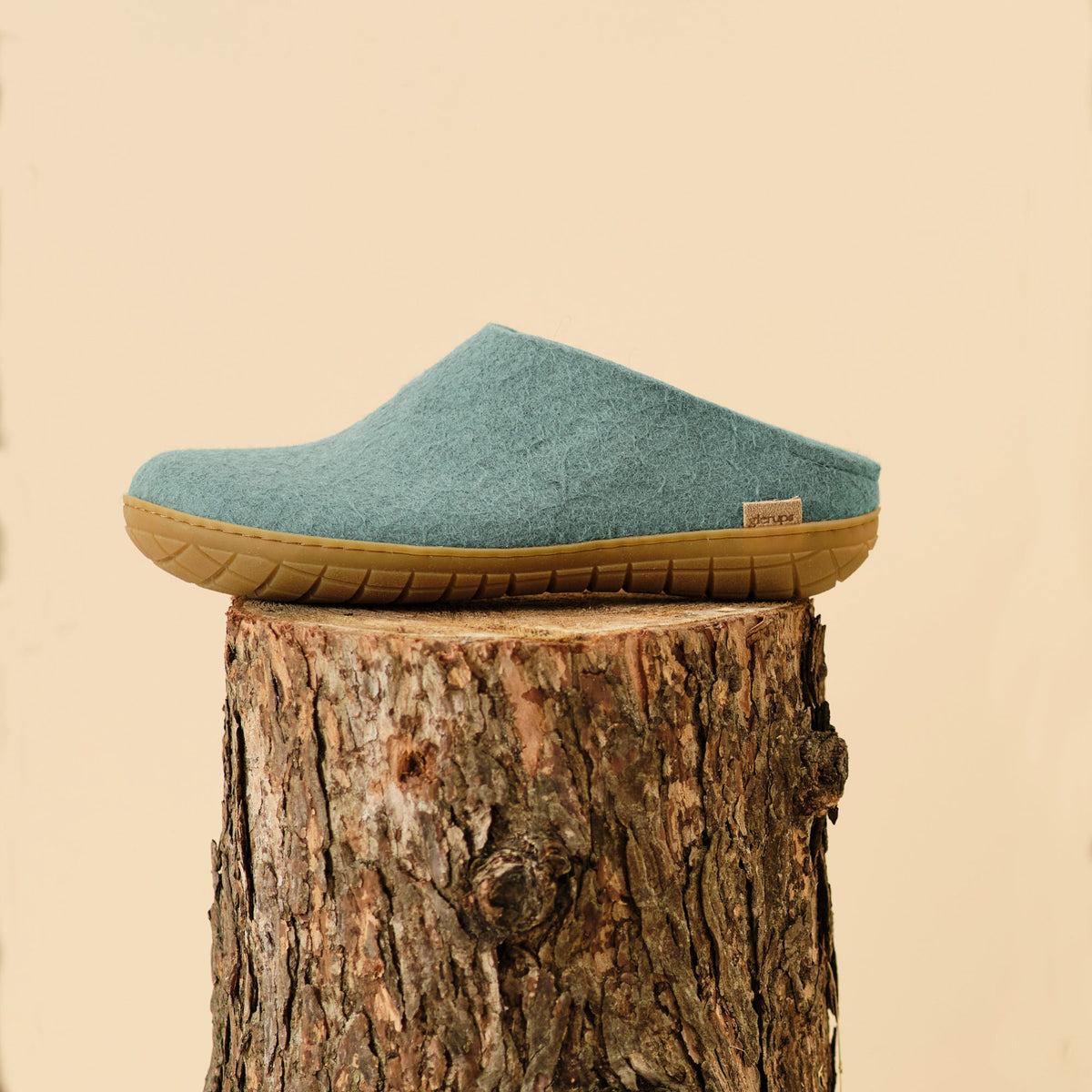 North sea slipper with rubber sole on a wooden stump against a beige background