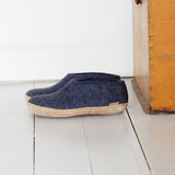 Pair of blue slippers on a white wooden floor next to a wooden cabinet.
