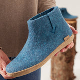 Blue felt boot with cork sole held by a person, blurred background