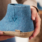 Blue felt shoe held by a hand with a blurred background