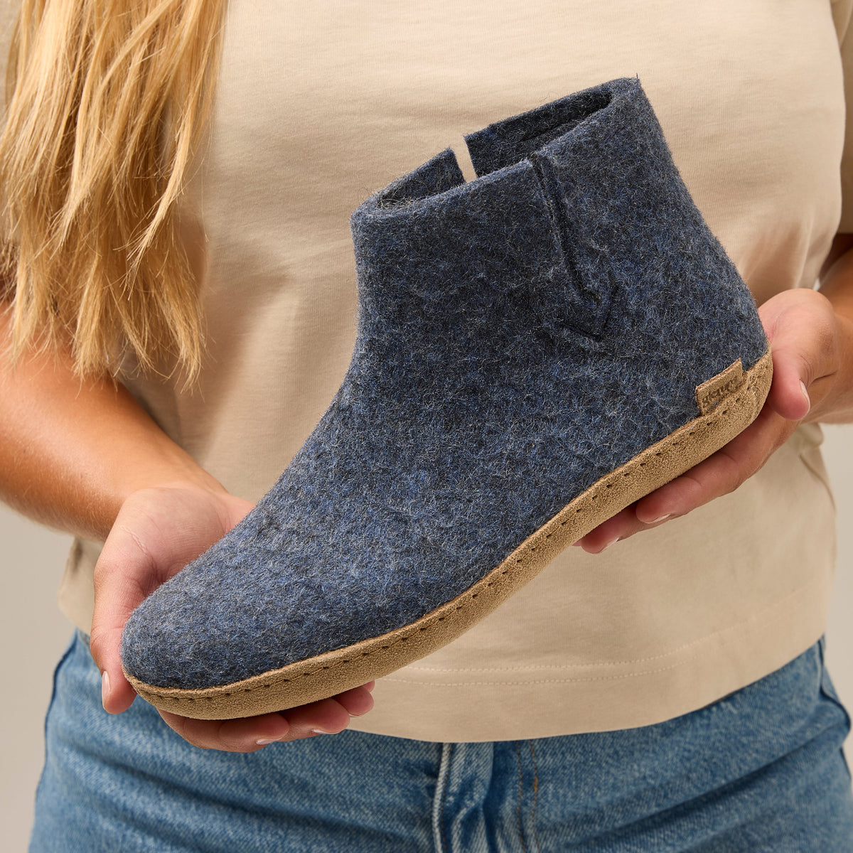 Person holding a blue suede shoe with a beige sole