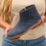 Person holding a blue suede shoe with a beige sole
