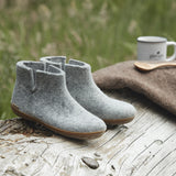Gray ankle boots on a wooden surface with a blurred natural background