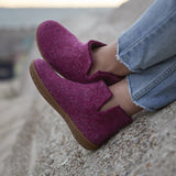 Cranberry Ankle boot worn with blue jeans on a stone surface.