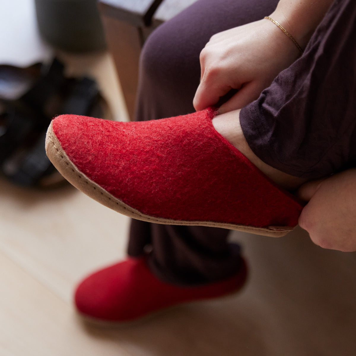 Red slipper being worn with a blurred indoor background