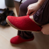 Red slipper being worn with a blurred indoor background