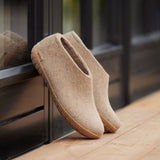Pair of sand slippers on a wooden surface with a blurred background