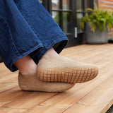 Person wearing sand slippers with honey rubber soles on a wooden deck.