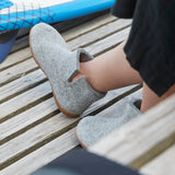 Gray ankle boot slippersslippers worn by a person sitting on a wooden deck.