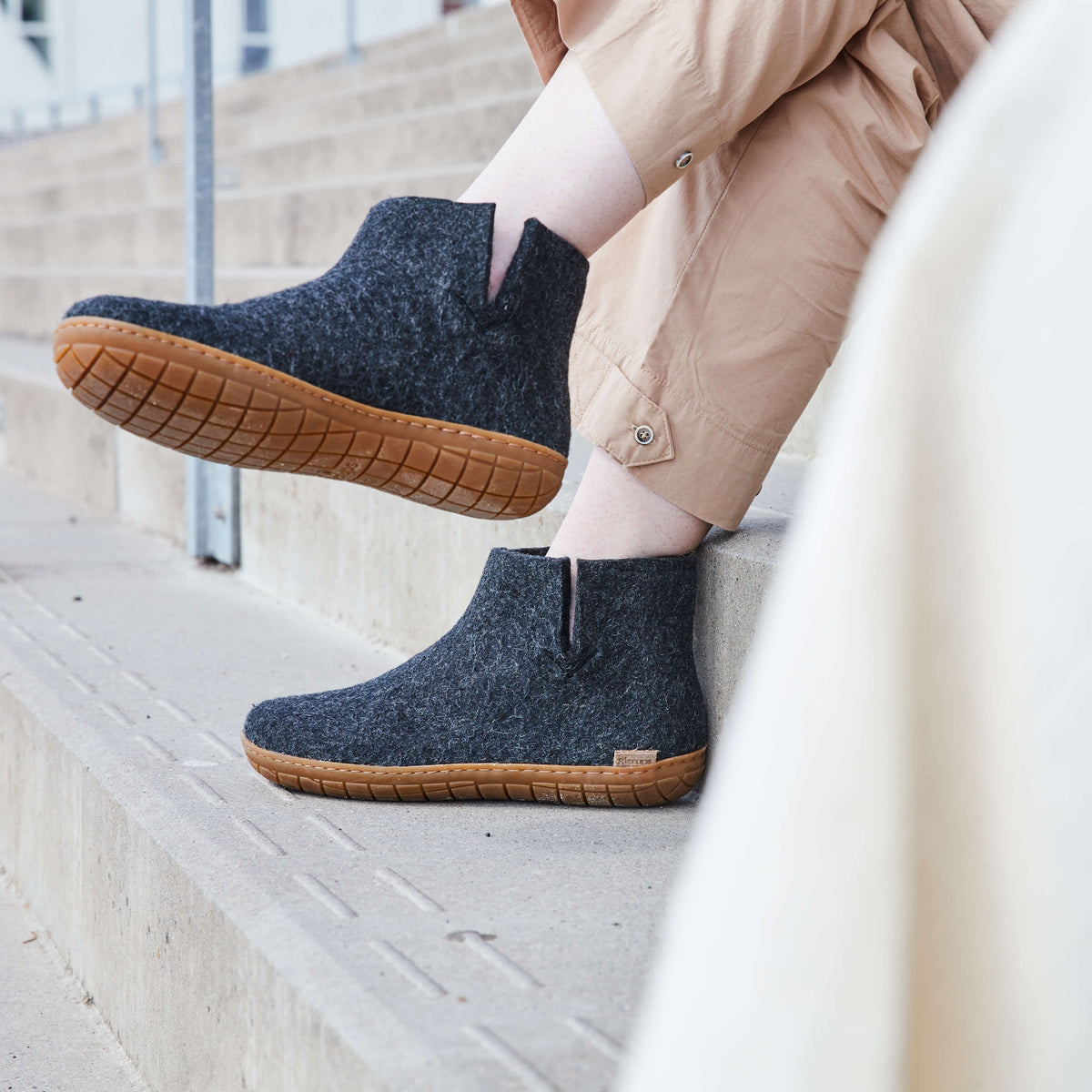 Person wearing dark gray ankle boots with  honey rubber soles on a staircase.