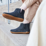 Person wearing dark gray ankle boots with  honey rubber soles on a staircase.