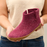 Person holding a Cranberry ankle boot with a beige background