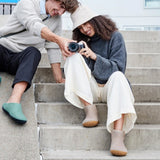 Two people sitting on steps, one holding a camera, wearing brown ankle boots