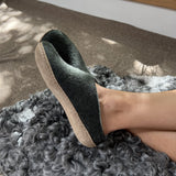 Person wearing a forest green slipper on a fluffy rug